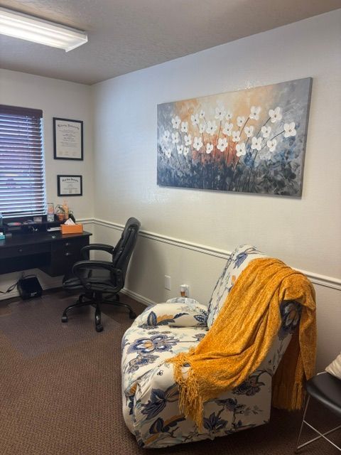 Counseling office with a floral chair, yellow blanket, and flower artwork
