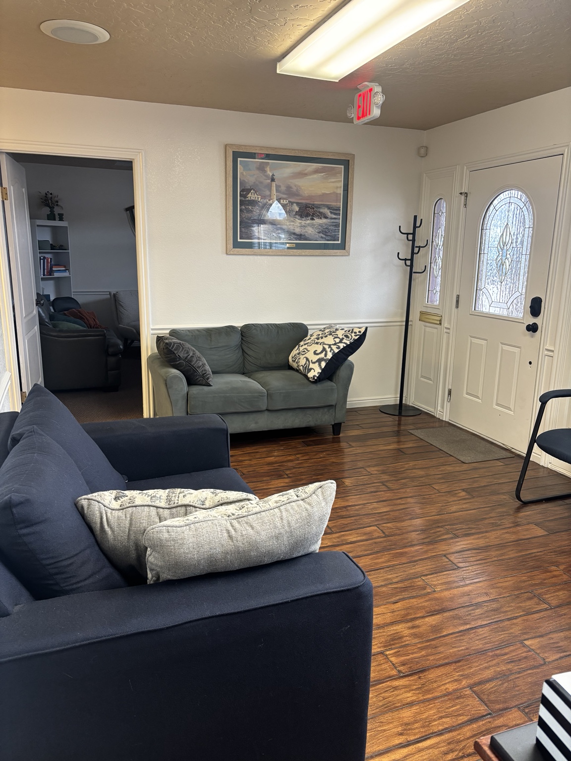 Waiting area with a blue couch, green loveseat, and front entrance