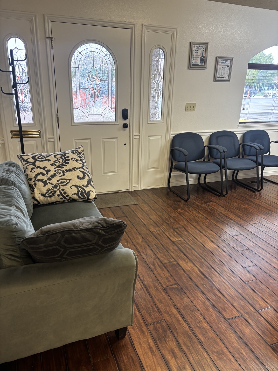 Waiting area with a green loveseat and blue chairs beside the front door