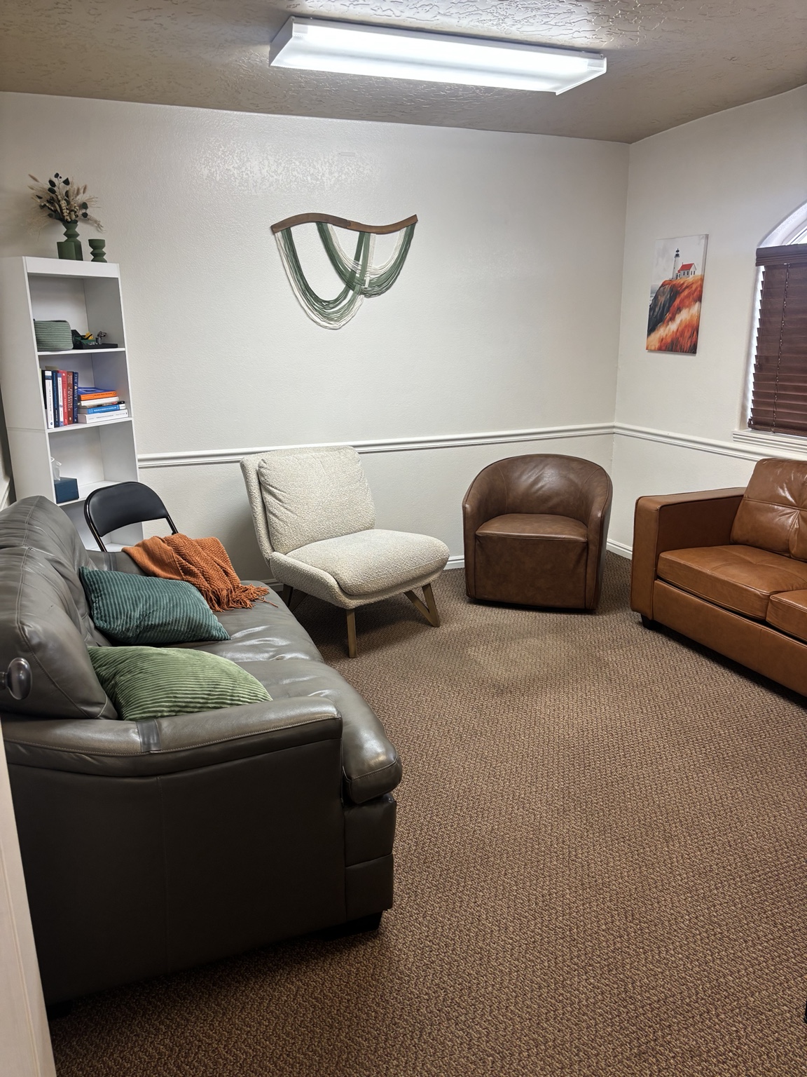 Counseling room with sofas, chairs, green cushions, and an orange blanket